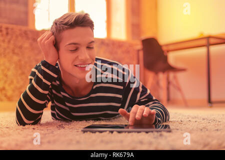 Pleased satisfied guy playing game on tablet Stock Photo