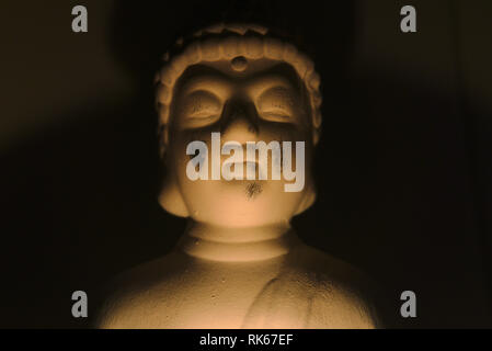 buddha holding a glass can with a candle in it. dark environment creepy and spiritual atmosphere. religion Stock Photo