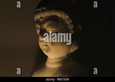 buddha holding a glass can with a candle in it. dark environment creepy and spiritual atmosphere. religion Stock Photo