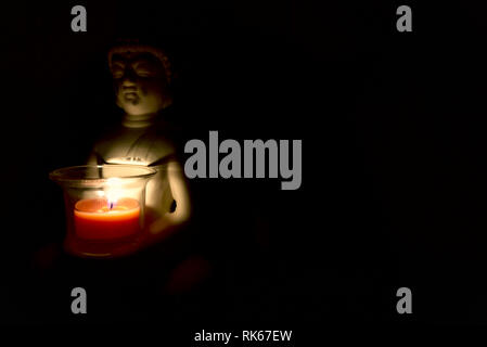 buddha holding a glass can with a candle in it. dark environment creepy and spiritual atmosphere. religion Stock Photo