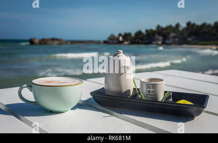 fancy cocktail served on a Japanese tea set and light blue cup with the ocean on the background, white and blue tones Stock Photo