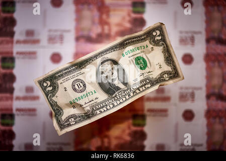 Two dollars on a blurred background of a banknote of the national currency of the Russian Federation. Stock Photo