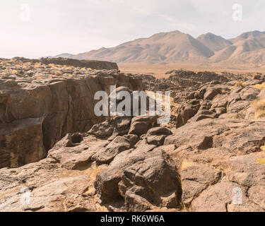 Rocky landscape with boulders and sparse vegetation under a cloudy sky ...