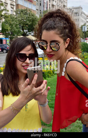 Two attractive young adult women on holiday looking at photo taken in tourist spot, Wenceslas Square, Prague Stock Photo