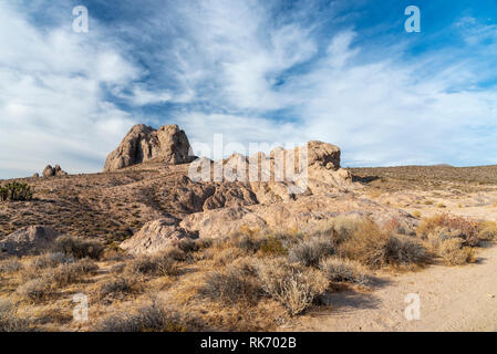 Desert landscape with rock formations under bright blue sky sky with white clouds. Stock Photo