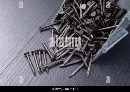 Metal nails on a dark workshop table. Accessories for DIY. Black background. Stock Photo