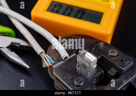 Work in a workshop on connections used in electronics. Computer cables and connectors rj44. Dark background. Stock Photo