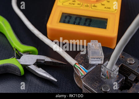 Work in a workshop on connections used in electronics. Computer cables and connectors rj44. Dark background. Stock Photo