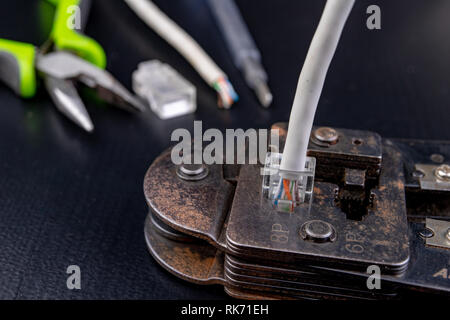 Work in a workshop on connections used in electronics. Computer cables and connectors rj44. Dark background. Stock Photo