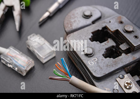 Work in a workshop on connections used in electronics. Computer cables and connectors rj44. Dark background. Stock Photo