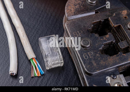 Work in a workshop on connections used in electronics. Computer cables and connectors rj44. Dark background. Stock Photo