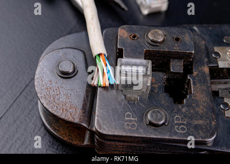 Work in a workshop on connections used in electronics. Computer cables and connectors rj44. Dark background. Stock Photo