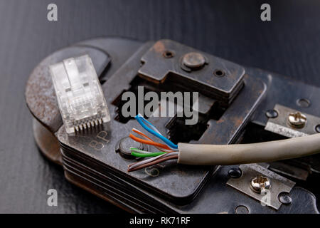 Work in a workshop on connections used in electronics. Computer cables and connectors rj44. Dark background. Stock Photo