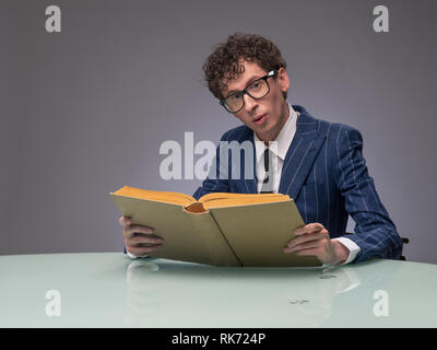 Funny man in suit and glasses reading old book and surprised Stock Photo
