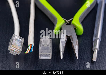 Work in a workshop on connections used in electronics. Computer cables and connectors rj44. Dark background. Stock Photo