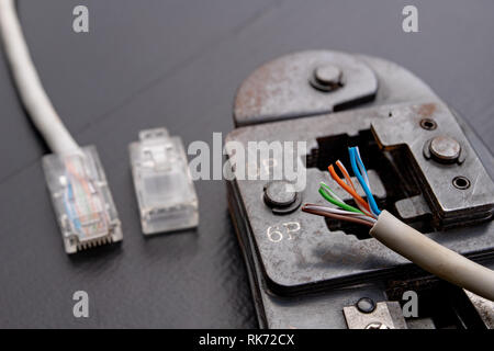 Work in a workshop on connections used in electronics. Computer cables and connectors rj44. Dark background. Stock Photo