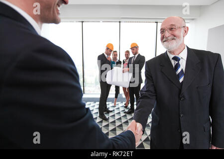 Business people shaking hands at meeting of architects and investors in office Stock Photo