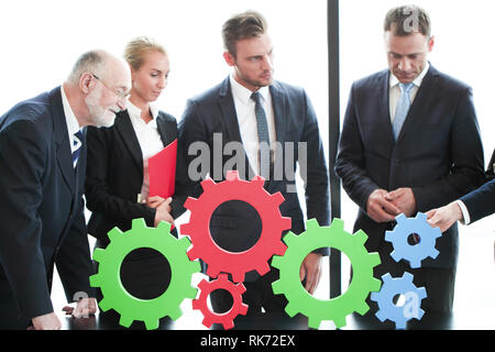 Business people assembling cogwheels, teamwork concept Stock Photo