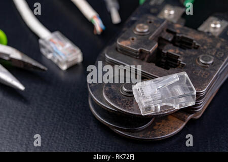 Work in a workshop on connections used in electronics. Computer cables and connectors rj44. Dark background. Stock Photo