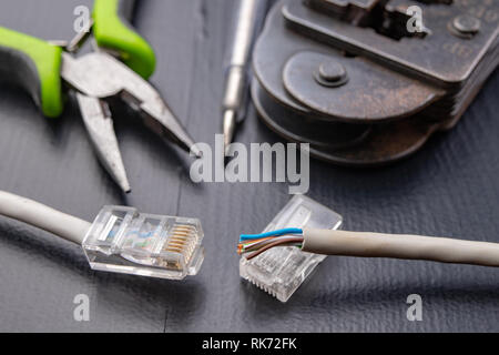 Work in a workshop on connections used in electronics. Computer cables and connectors rj44. Dark background. Stock Photo