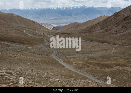Mountain biking the narrow dirt road ahead winding over the barren mountains of the Khardungla Pass in Tibet Stock Photo