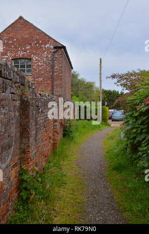 Old Rustic Red Brick Building with Poppies Growing on the Wall. Stock Photo