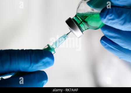 Physician injector arms in sterile uniform holding syringe Stock Photo