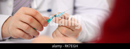 Physician injector arms in sterile uniform holding syringe Stock Photo