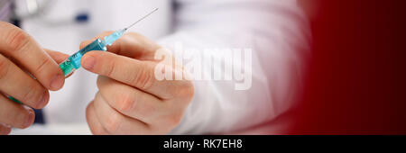 Physician injector arms in sterile uniform holding syringe Stock Photo