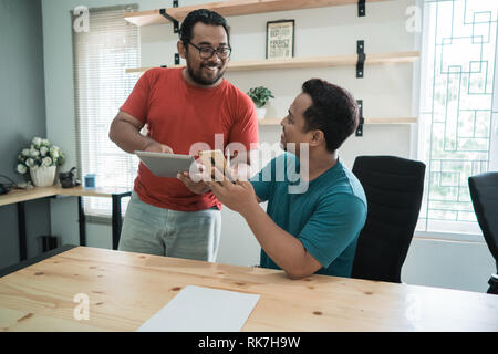 portrait of briefing two male workers with their hands holding digital tablets and smartphones in the office Stock Photo
