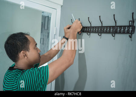 portrait of asian young man working install a hangers on the wall Stock Photo