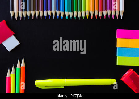 School and drawing supplies, on black background. Colored pencils, pencils, sticky note, eraser, sharpener and highlighter. With copy space. Stock Photo
