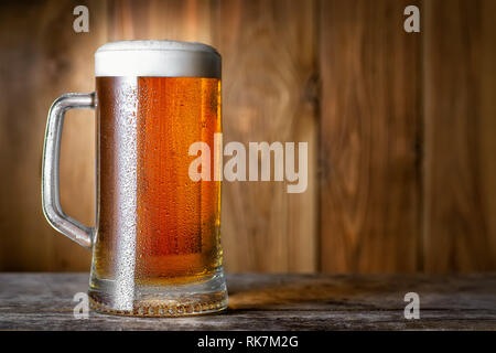 cold light beer in mug with water drops on wooden table Stock Photo