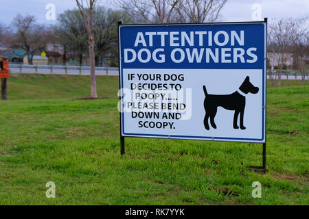 Sign requesting dog owners clean up after their pet: 'Attention Dog Owners. If your dog decides to poopy please bend down and scoopy.' Stock Photo