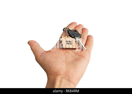 Isolated male hand holding in hand chrome key with wooden house tagged to key ring. Abstract illustration of hand handing over key with little house a Stock Photo