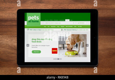 The website of Pets at Home is seen on an iPad tablet, which is resting on a wooden table (Editorial use only). Stock Photo