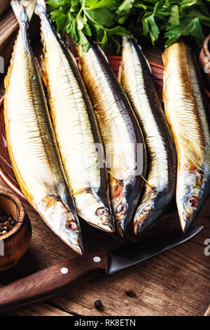 Appetizing smoked fish on kitchen board.Smoked saury.Smoked fish with spices Stock Photo