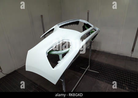 Repair of the rear bumper of a white car after an accident with the help of multi-colored putty in a workshop for painting vehicles in a special chamb Stock Photo