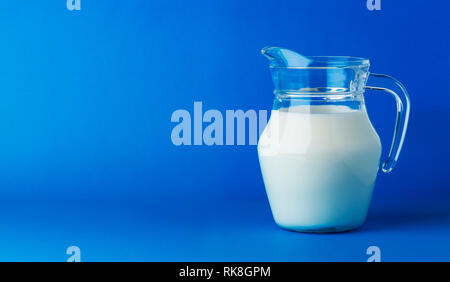 Glass jug of milk isolated on blue background with copy space Stock Photo