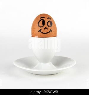 Brown egg with a painted face, on a stand, on a white background Stock Photo