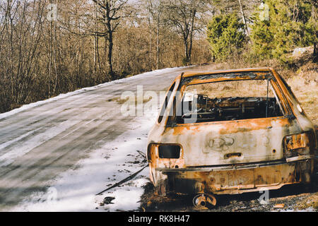 Burnt out car by side of icy road, Sweden, Scandinavia Stock Photo