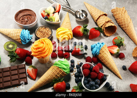 Vanilla frozen yogurt or soft ice cream in waffle cone. Diffrent flavor ice cream with kiwi and pistachio, mango and lemon, blueberry and blackberry Stock Photo
