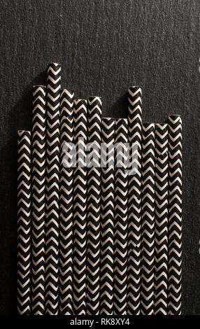 Black contrast drinking straws. Background of patterned straws on dark stone table. Arranged straws next to each other. Concept for Summer time and dr Stock Photo