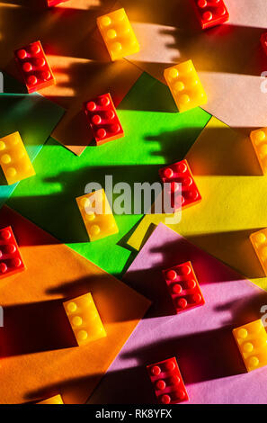 Plastic geometric cubes. Construction toys on geometric shapes paper multi colored background. Arranged in rows. Children's toy. Circle geometric shap Stock Photo
