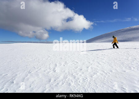 Young boy in yellow winter jacket walking in deep snow in snow covered winter mountain landscape, Dobratsch, Austria Stock Photo