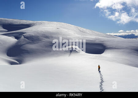 Young boy in yellow winter jacket walking in deep snow in snow covered winter mountain landscape, Dobratsch, Austria Stock Photo