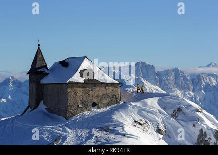 Mother and son standing by a beautiful church covered in snow with an amazing view over the mountains, Dobratsch, Austria Stock Photo