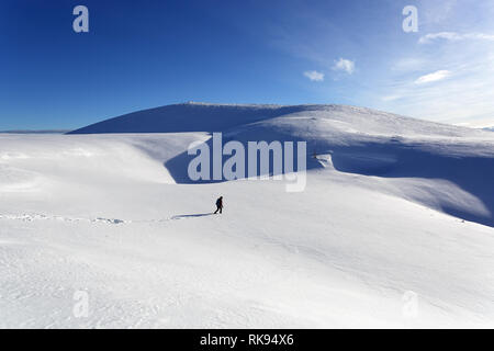 Woman hiking in deep snow on snow covered mountain, Dobratsch, Austria Stock Photo