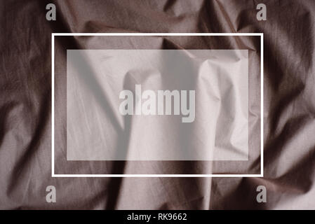 Drawn white frame against a background folds of brown fabric. Creative layout. Texture use as an abstract background. Luxurious background design. Stock Photo