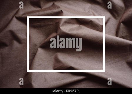 Drawn white frame against a background folds of brown fabric. Creative layout. Texture use as an abstract background. Luxurious background design. Stock Photo